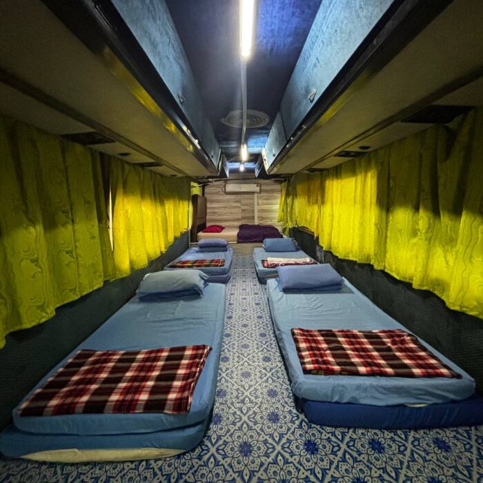 Ruang tidur di dalam Bas Sunflower dengan langsir kuning dan katil selesa.