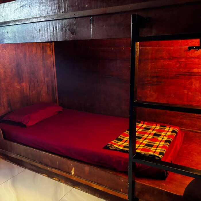Ruang tidur berbentuk kapsul kayu yang selesa dengan cadar merah di Kuala Selangor Cabin Camp (KSCC